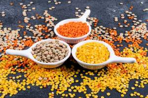 different-lentils-mini-white-spice-bowls-black-stone-table-side-view